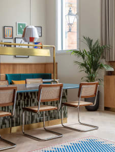 Modern dining room with concrete floor, wooden chairs, glass table, and decorative pendant light.