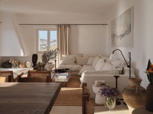 Minimalist living room with neutral tones, featuring a cozy sofa, wooden coffee table, and artistic wall decor.