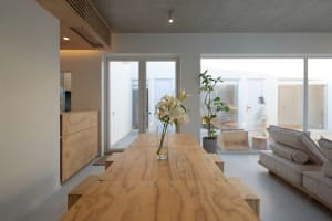 A minimalist living room with wooden furniture and a vase of flowers on the table.
