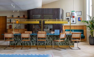 A modern restaurant bar with wooden and cane furniture, copper railings, and glass panels.