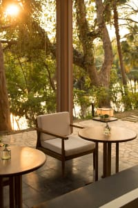 A cozy cafe featuring a wooden chair and tables with a serene outdoor view.