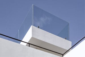 Contemporary building exterior featuring a glass balcony with white walls.