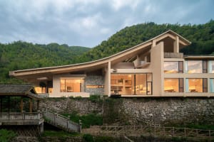 A modern residential exterior with stone walls, large glass windows, and minimalist architectural design.
