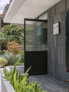 A modern building exterior featuring a black door with glass panels and a concrete facade.