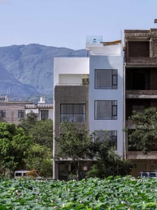 Modern minimalist residential building with sustainable design elements, featuring concrete exterior and large windows.