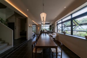 Modern restaurant interior featuring wooden tables, glass windows, and concrete floors.