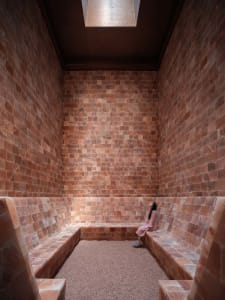 A minimalist spa room with walls lined with pink salt-rock tiles.