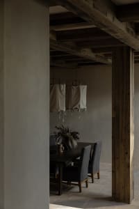 A minimalist dining room featuring wooden furniture and fabric lanterns hanging from the ceiling.