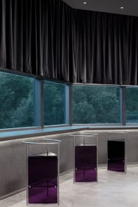 Modern hotel lobby with glass and metal furniture and black curtains.