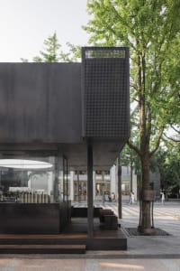 A modern building with a black metal exterior features a sleek, minimalist design.