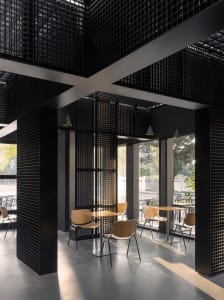 A modern cafe interior with black metal structures and glass walls.