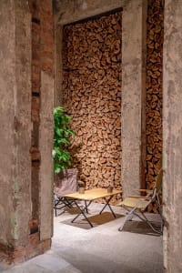 Industrial-style interior design featuring stacked firewood and seating area.