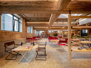 An industrial-style office-cave with concrete walls and red-cloth-covered furniture