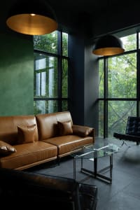 A modern living room featuring a brown leather sofa with glass coffee table and concrete walls.