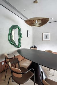 Modern interior design featuring a metallic dining table with wooden chairs and a contemporary art piece.