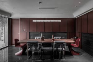 A modern dining room with wooden furniture, featuring a long wooden table surrounded by chairs of various styles.