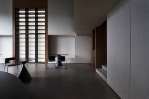 Modern, minimalist interior with concrete walls and floor, featuring a sleek, black dining table and chairs.