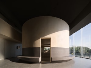 Minimalist living room with concrete walls and floor, featuring clean lines and natural light.