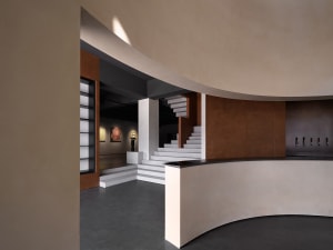A modern architectural museum with concrete walls and a metal staircase.