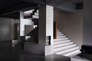 A minimalist interior design featuring concrete elements and industrial lighting.