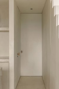 A minimalist doorway made of concrete with a simple wooden handle.