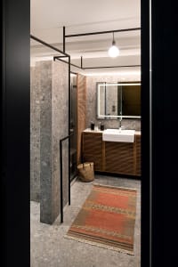 A minimalist bathroom featuring marble surfaces and a sink with a wooden cabinet.