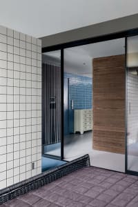 Modern bedroom featuring a wicker bed, blue tiles, and wood paneling.