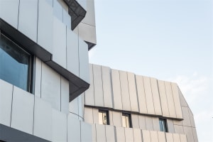 Modern buildings featuring metal cladding surfaces against a clear sky.