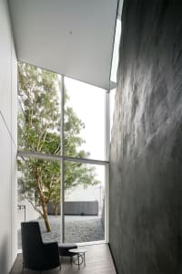 A minimalist residential interior featuring concrete walls and large glass window.