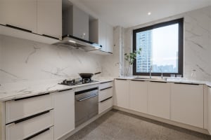 Contemporary, minimalist kitchen with marble countertops, white cabinets, and stainless steel appliances.