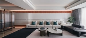 Modern living room featuring beige leather sofas, teal throw pillows, and paneled wood accent wall.