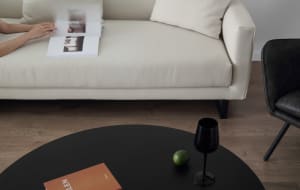A modern living room with a white sofa, black coffee table, and black leather chair.