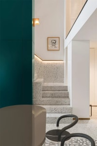 Modern staircase with speckled white terrazzo tiles, white walls, and a black chair.