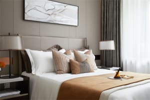 Modern bedroom featuring a brown and white lampshade and black and gray striped pillows.