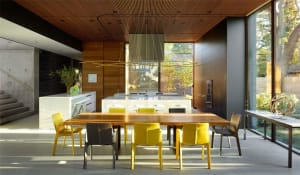 Modern kitchen with wooden table, yellow chairs, and metal accents