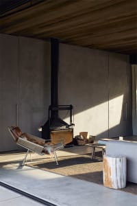 Industrial-style living room featuring a concrete floor and minimalist decor, including a fireplace and lounge chair with fur