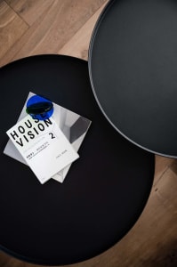 A sleek, modern black side table with a metallic finish, featuring a minimalist design and a blue circular object on top.