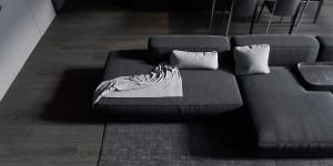 A modern living room featuring a grey fabric sectional couch with a blanket and pillows.
