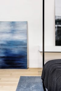 A minimalist interior design featuring a large abstract blue painting on a wall.