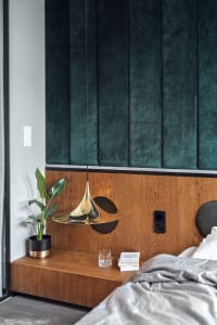 Modern bedroom featuring a wooden headboard and green fabric wall