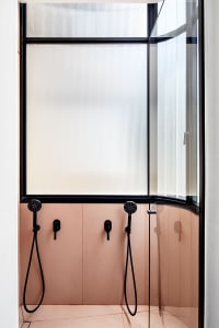 A minimalist bathroom with a glass door and pink floor tiles.