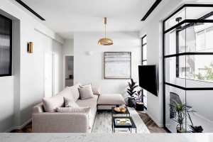 Modern living room with minimalist decor, neutral tones, and sleek white pendant light fixture.