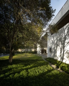 A modern residential space featuring concrete structures and lush greenery, with a path leading to a building entrance.