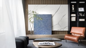 A modern living room featuring a blue and white abstract painting with marble walls and a leather chair.