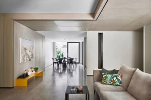 A modern living room with concrete walls and a glass partition.
