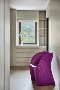 A modern living room featuring a purple plastic armchair, with a window overlooking greenery.