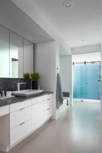 Modern bathroom with a marble countertop and concrete flooring.