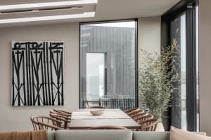 Modern dining room with wooden furniture, large glass windows, and indoor plants.