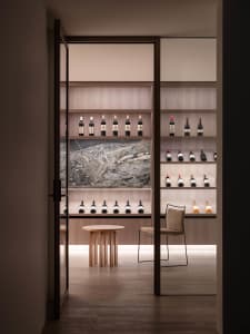 A minimalist wine storage room featuring wooden shelves, glass bottles, and a marble backsplash.