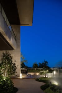 A nighttime view of a minimalist hotel terrace featuring mixed materials and sleek design elements.